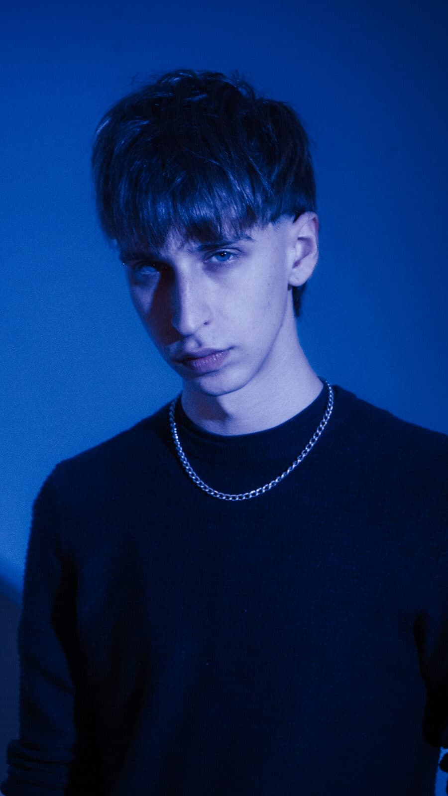 KAIF agachado, fondo cyan